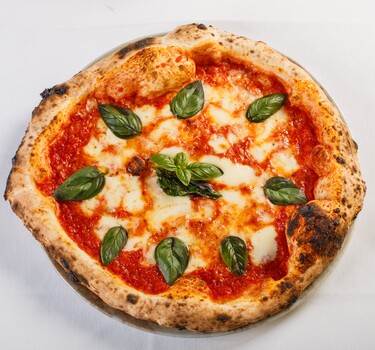 Pizza margherita napoletana con sugo di pomodoro, mozzarella di bufala e basilico fresco servita in una tipica pizzeria napoletana